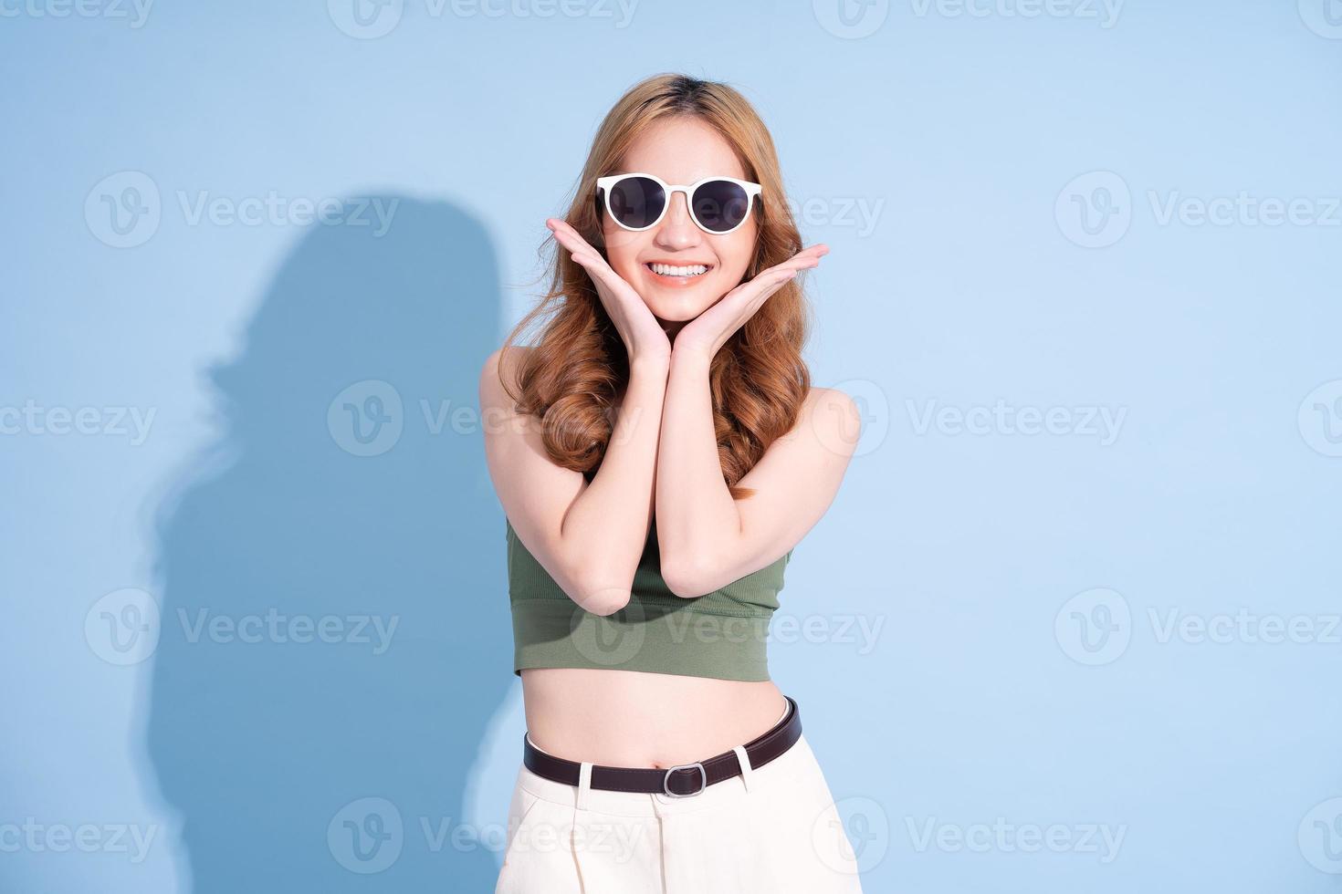 Beautiful young Asian woman on blue background, summer vacation concept photo