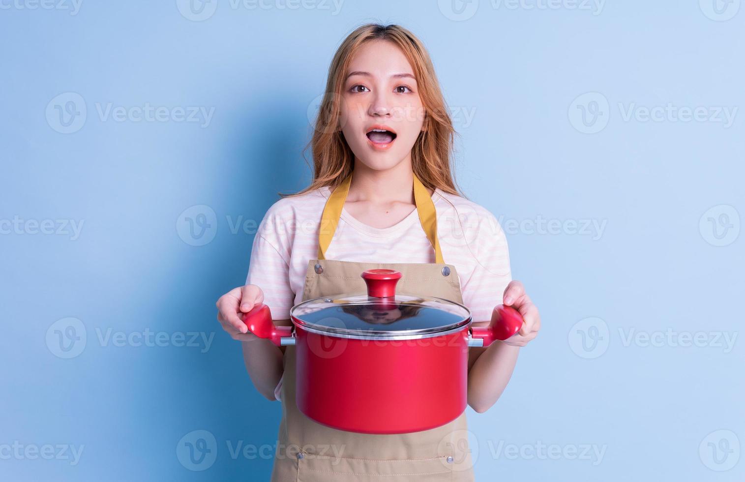 imagen de una joven asiática sosteniendo una olla con fondo azul foto