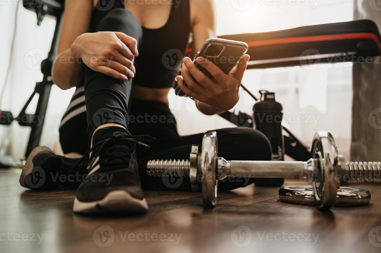 lose up of woman using smart phone while workout in fitness gym. Sport and Technology concept. Lifestyles and Healthcare theme. photo