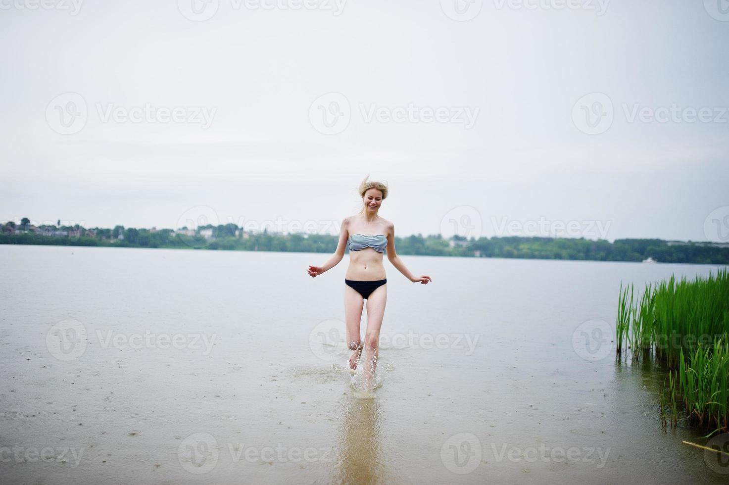 Portrait of a beautiful bikini model standing and posing in the water. photo