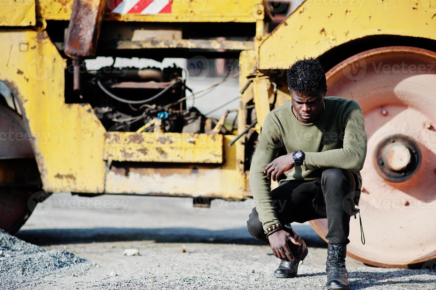 Portrait of an attractive black african american man posing next to the industrial machinery. photo