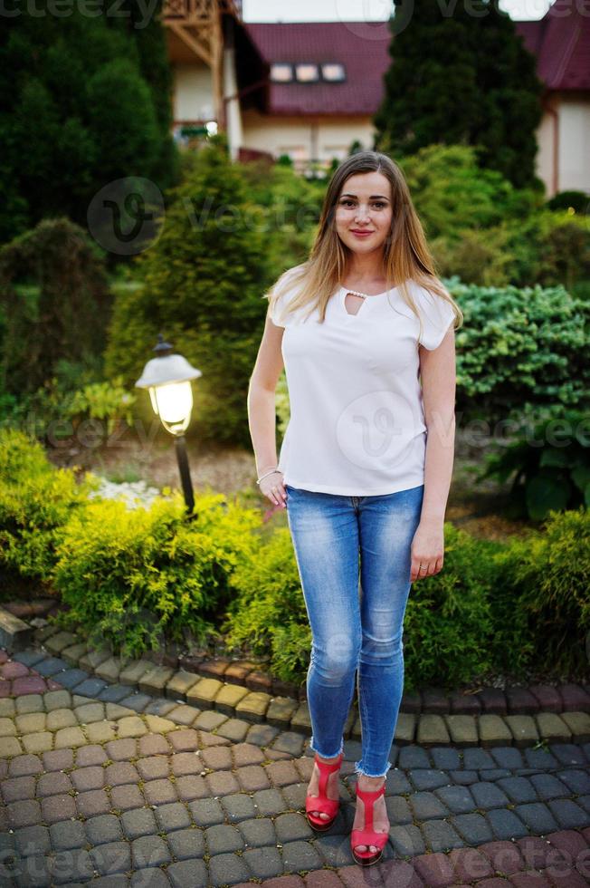 fabulosa dama de honor con jeans y camiseta blanca posando afuera en la despedida de soltera. foto