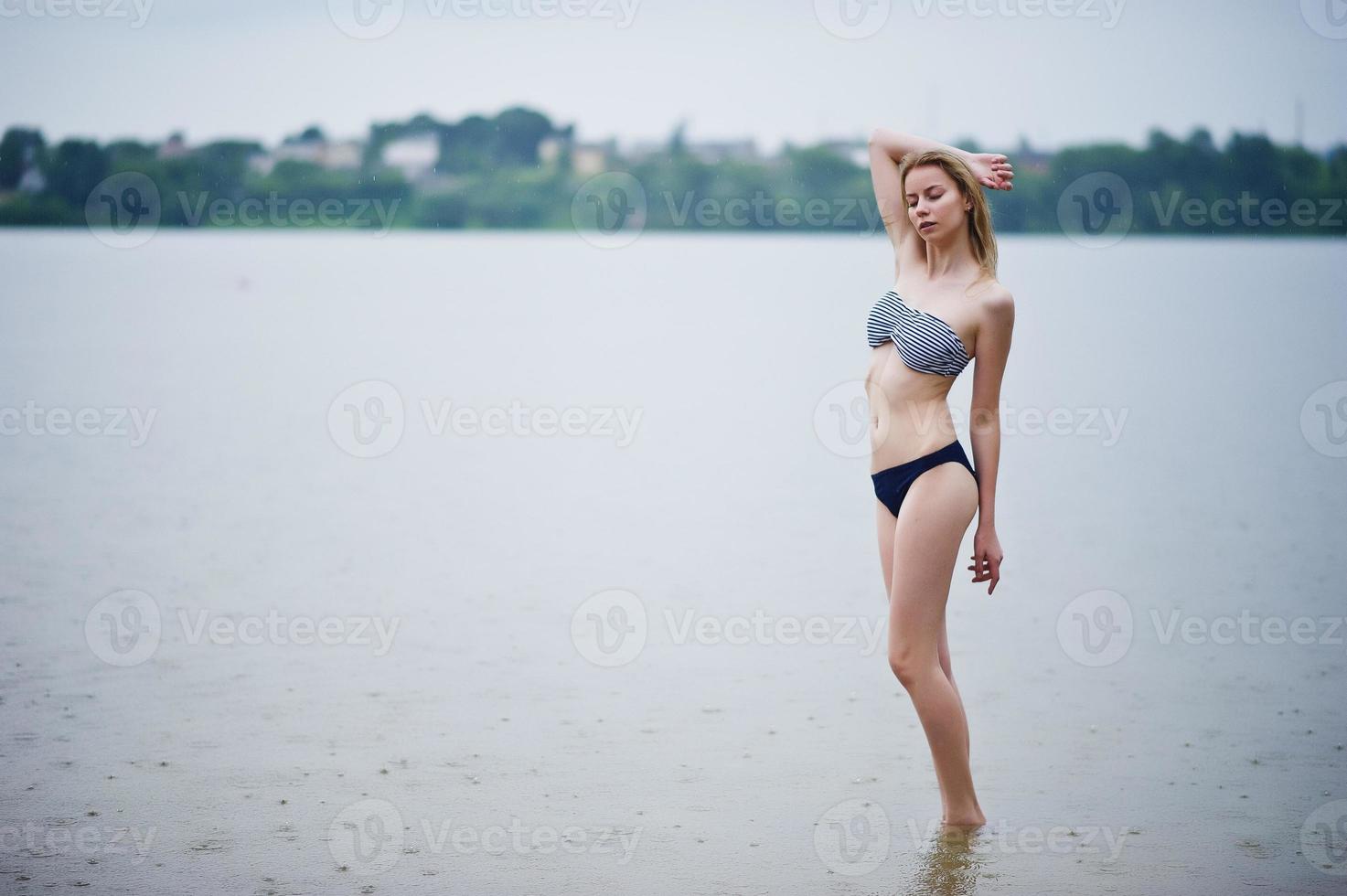 Portrait of a beautiful bikini model standing and posing in the water. photo