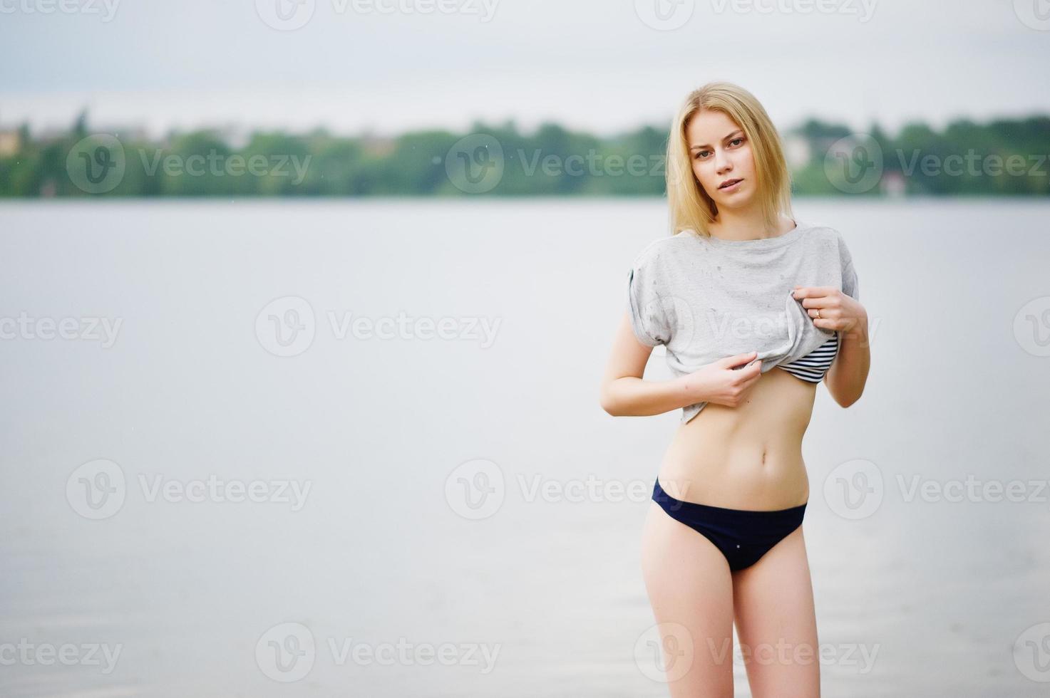 retrato de una modelo alta de aspecto fantástico con camiseta y bikini caminando en el lago. foto