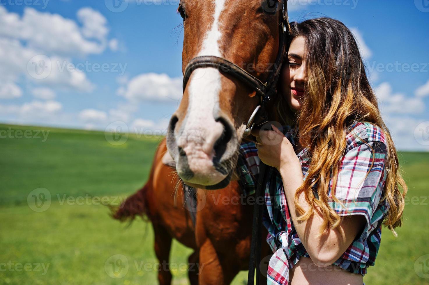 Young pretty girl stay with horse on a field at sunny day. photo