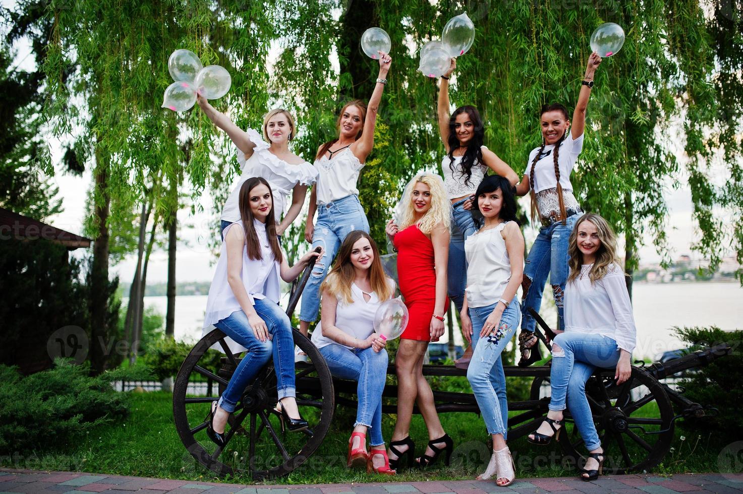 Comany of young women posing outside with inflated condoms at bachelorette party. photo