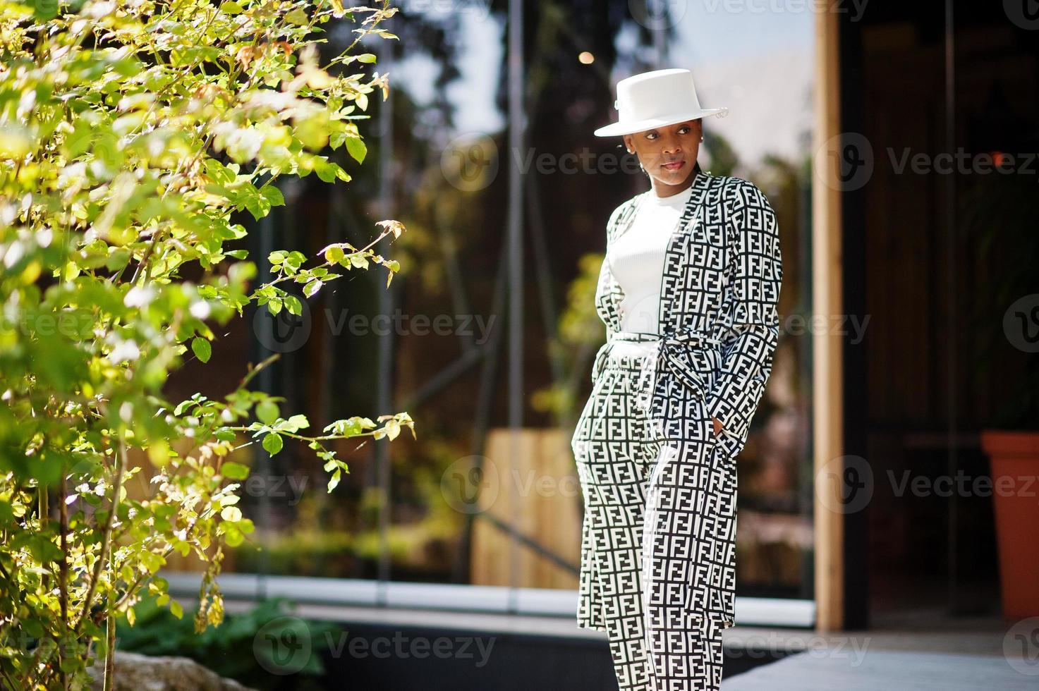 Beautiful african american woman natural makeup wear fashion clothes casual black and white dress code office style total blouse and pants suit and hat. photo