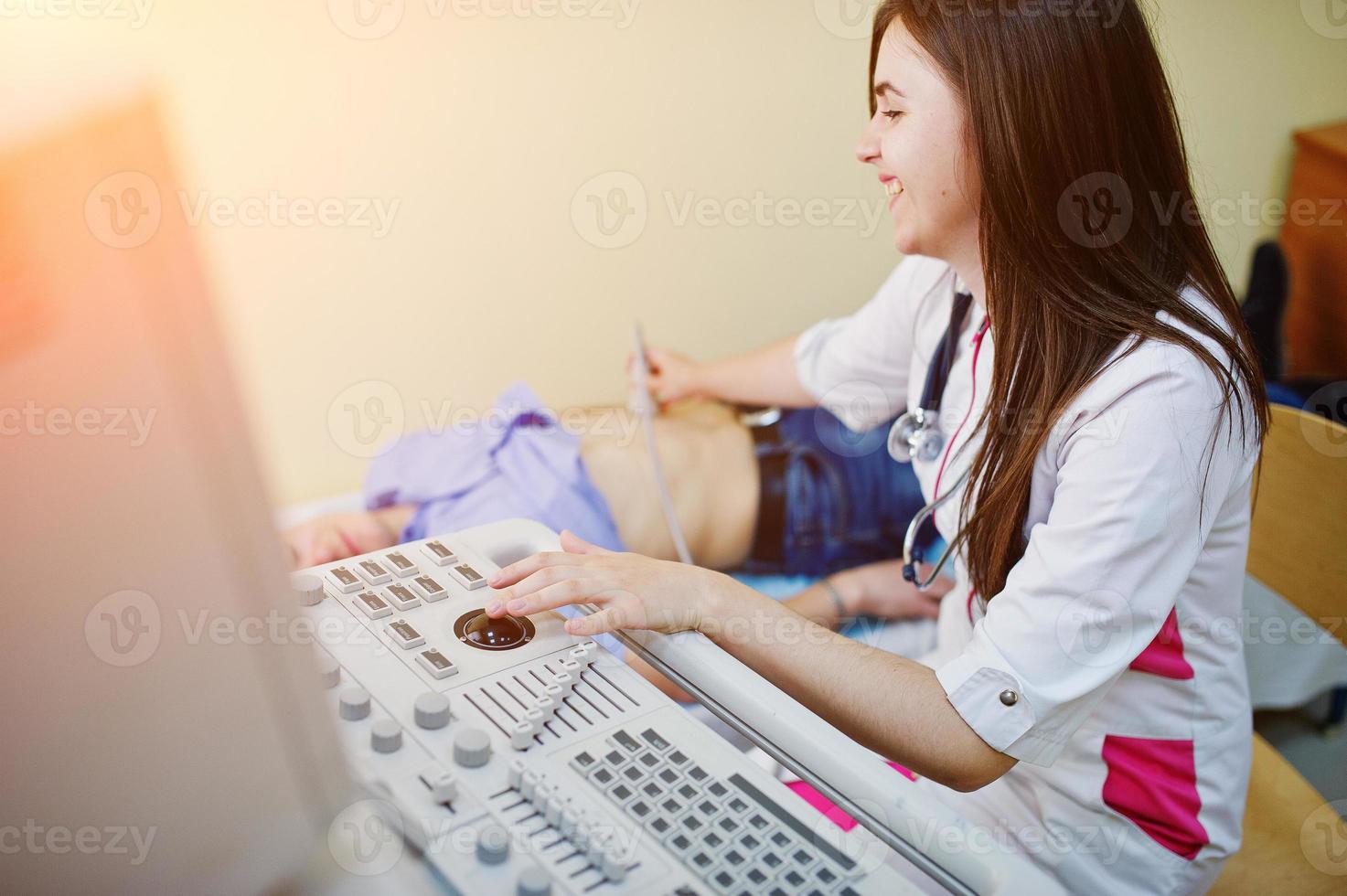 Beautiful young doctor doing diagnostic sonography on a patient. photo