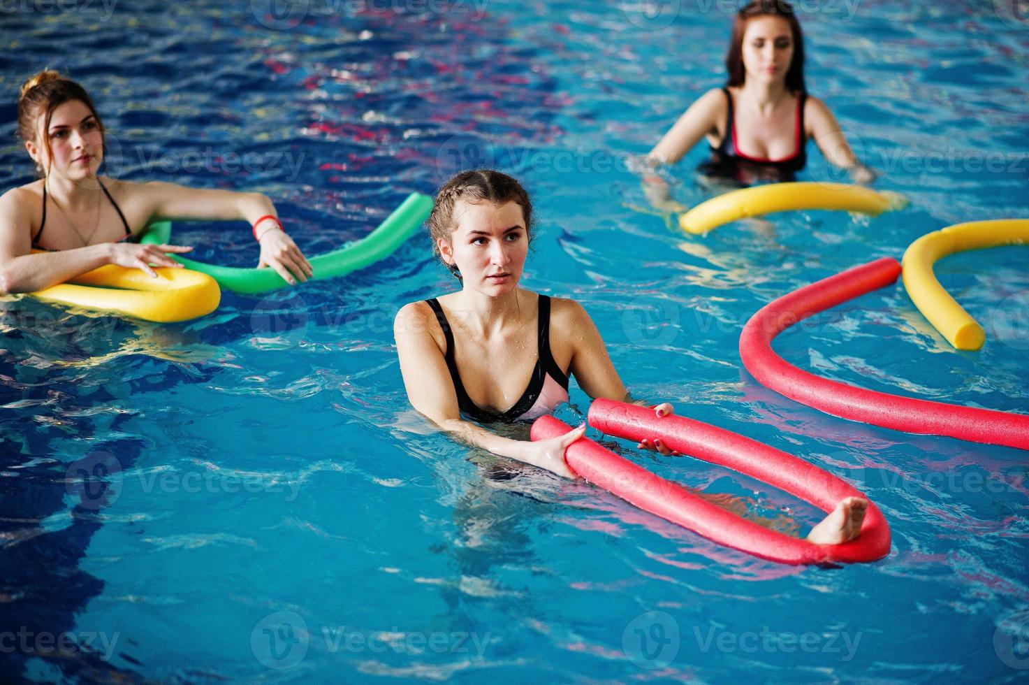 Fitness group of girls doing aerobical excercises in swimming pool at aqua park. Sport and leisure activities. photo