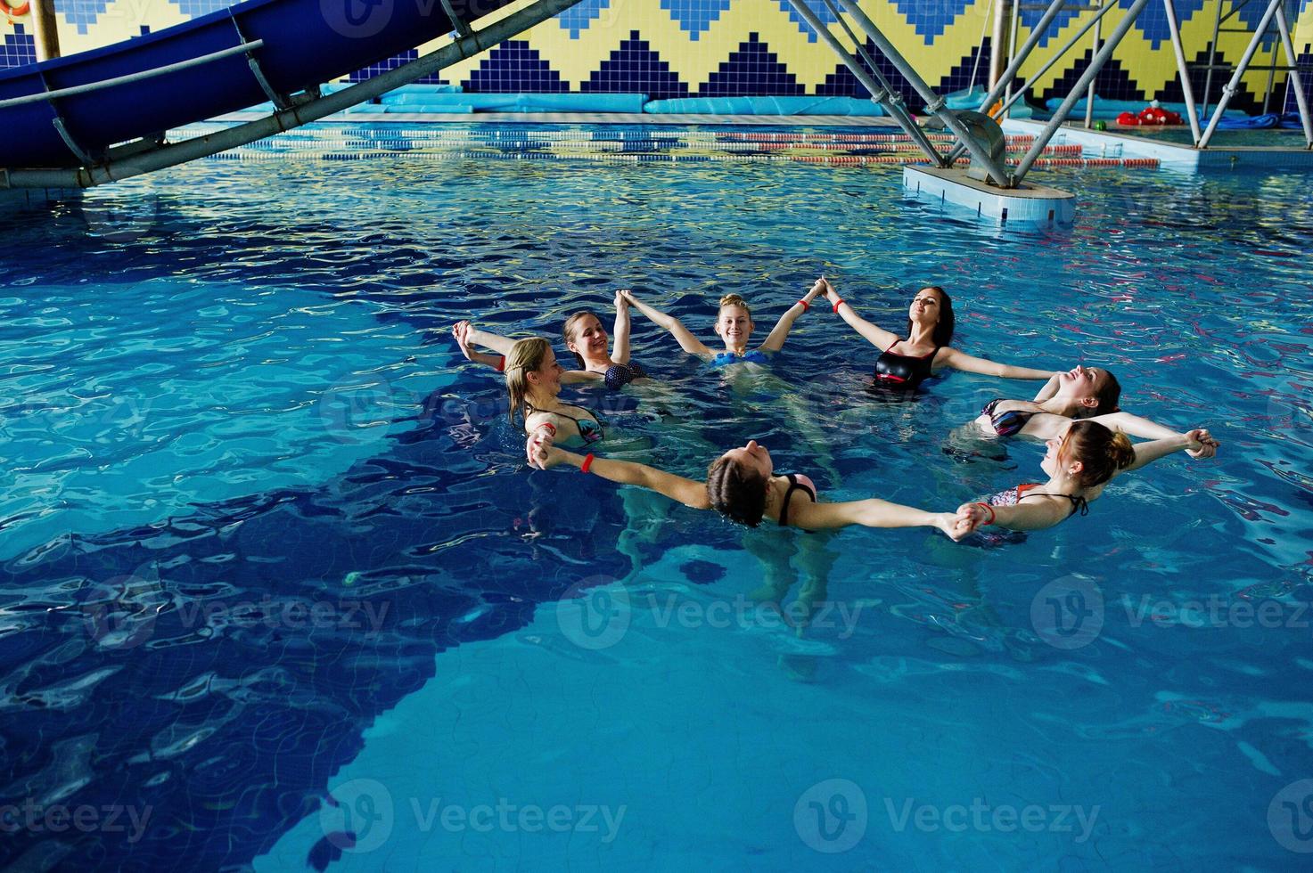 Fitness group of girls doing aerobical excercises in swimming pool at aqua park. Sport and leisure activities. photo