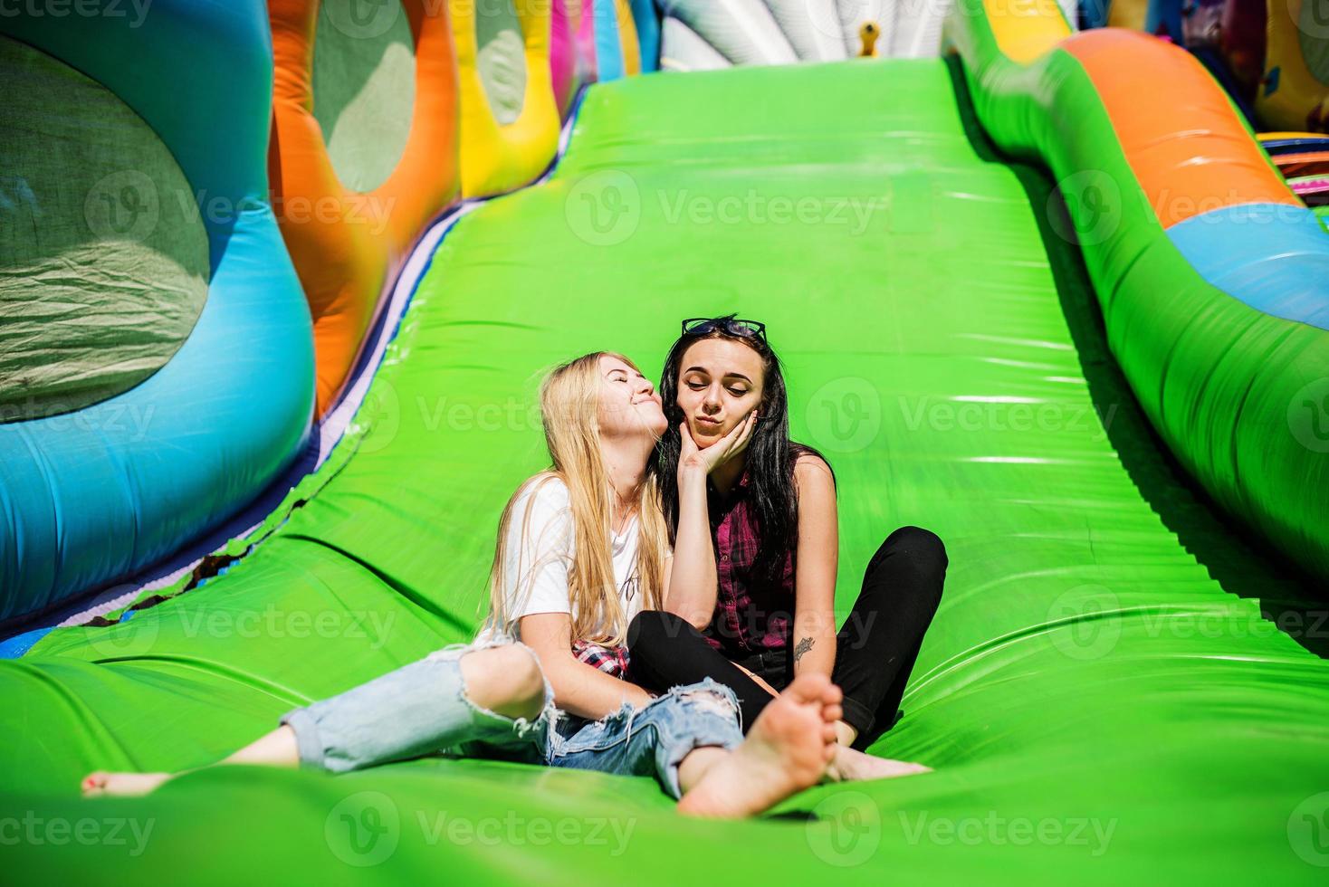 Gorgeous girls having fun on a slide on a sunny day. photo
