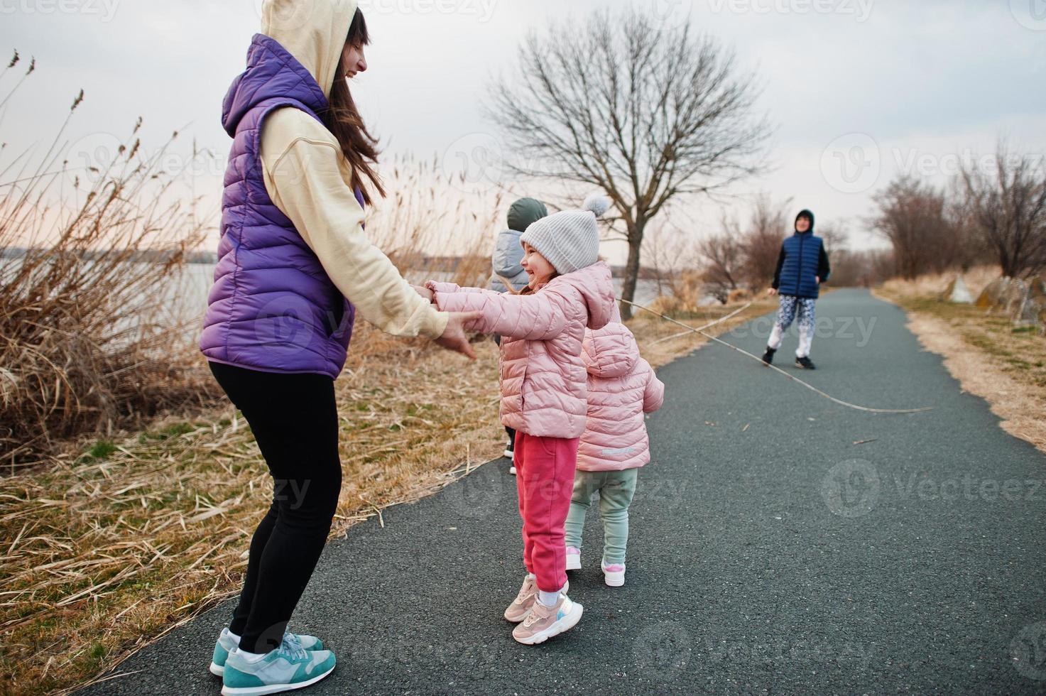 Mother with kids jump and having fun on the path by the lake. photo