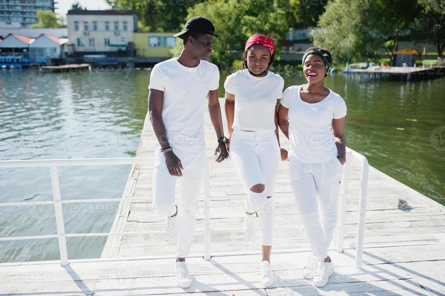 tres elegantes amigos afroamericanos, vestidos con ropa blanca en el muelle  de la playa. moda callejera de jóvenes negros. hombre negro con dos niñas  africanas. 7219373 Foto de stock en Vecteezy