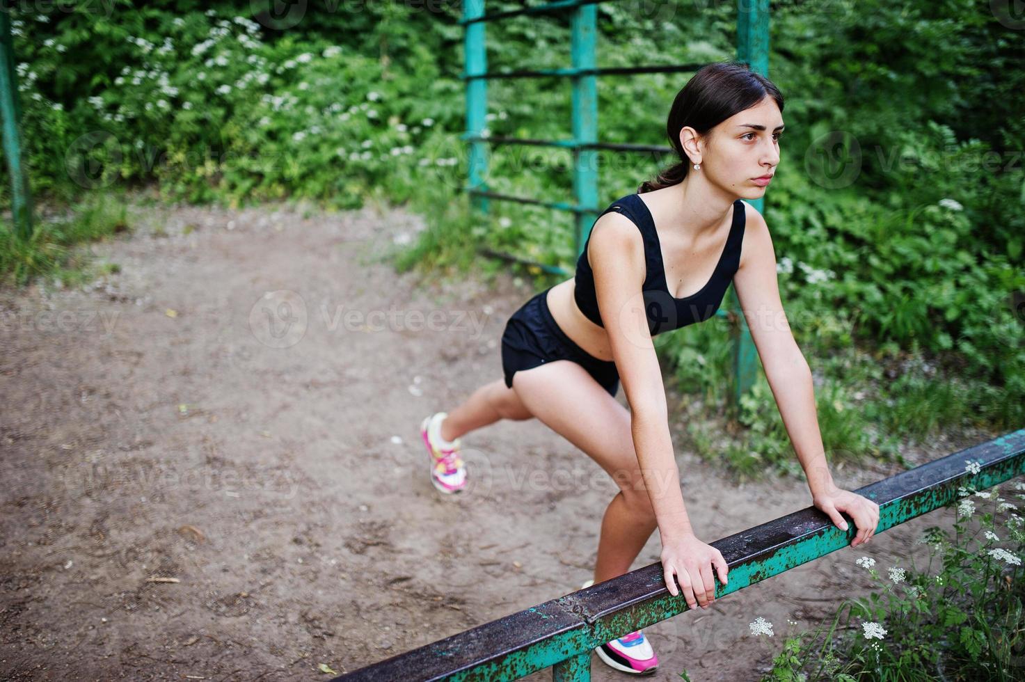 Sport girl at sportswear exercising at horizontal bar exercises in a green park and training at nature. A healthy lifestyle. photo