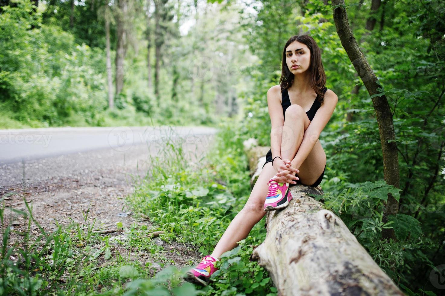 Sport girl at sportswear having rest in a green park after training at nature. A healthy lifestyle. photo