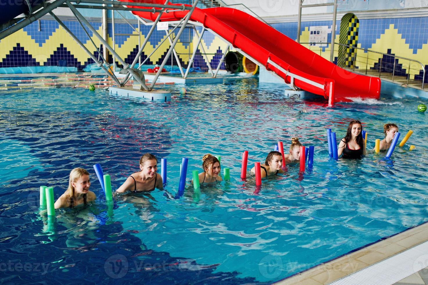 grupo de fitness de chicas haciendo ejercicios aeróbicos en la piscina en el parque acuático. actividades deportivas y de ocio. foto