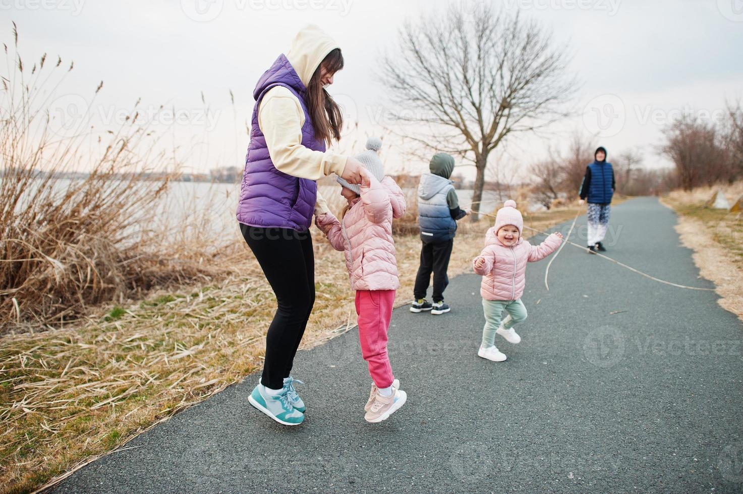 Mother with kids jump and having fun on the path by the lake. photo