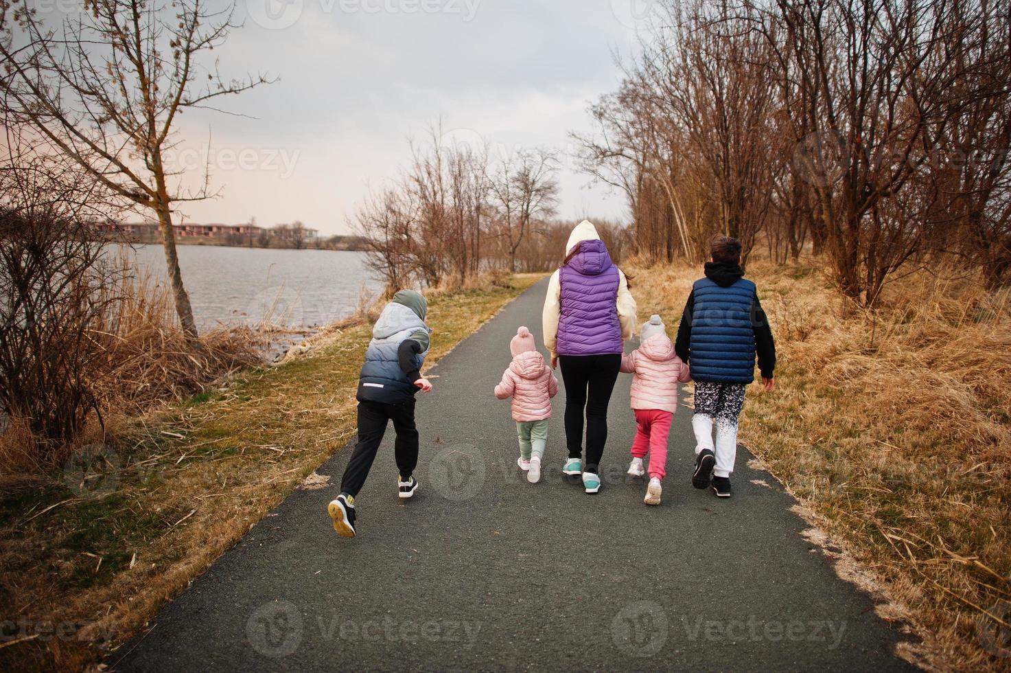 Back of mother walking with kids on the path by the lake. photo