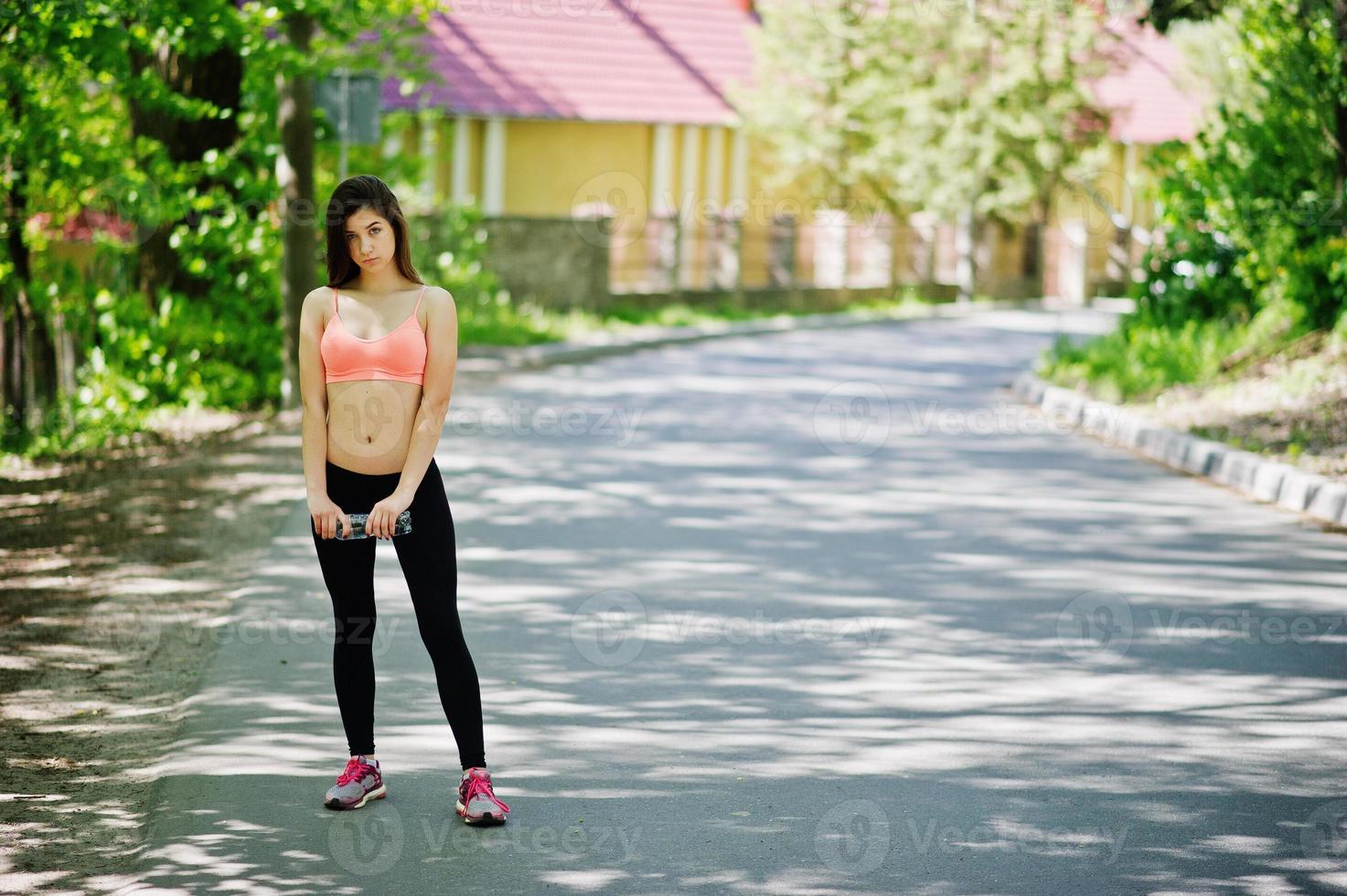 chica deportiva fitness en ropa deportiva con botella de agua en la calle, deportes al aire libre, estilo urbano. foto