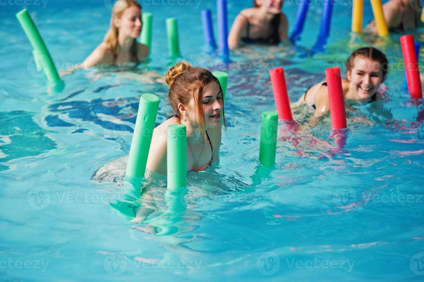 Fitness group of girls doing aerobical excercises in swimming pool at aqua park. Sport and leisure activities. photo