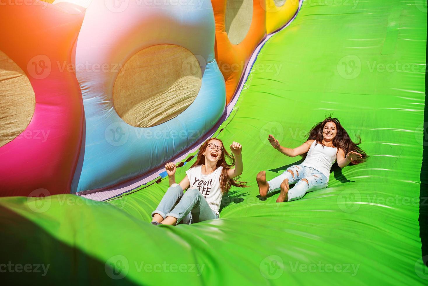 Gorgeous girls having fun on a slide on a sunny day. photo