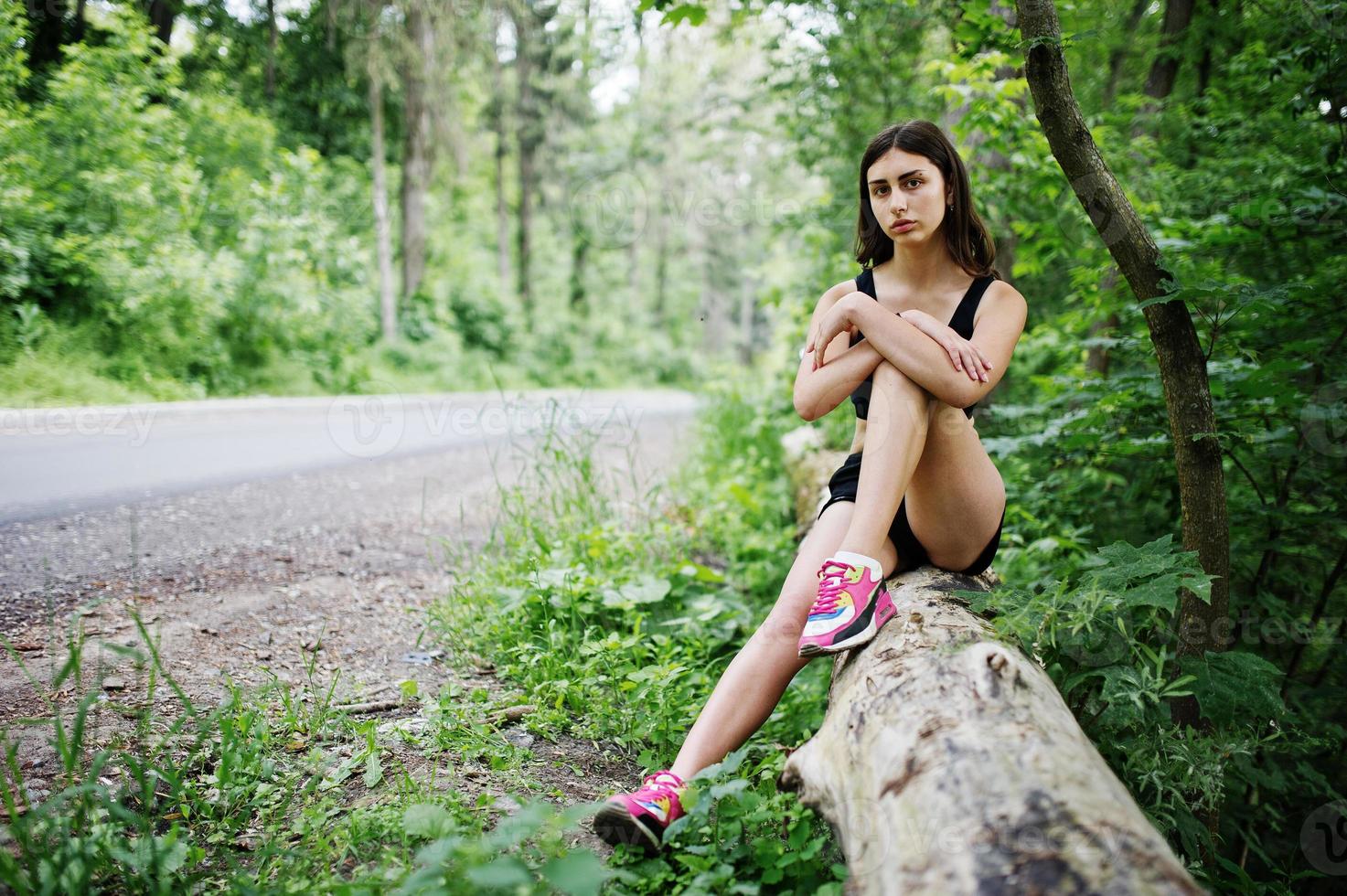 Sport girl at sportswear having rest in a green park after training at nature. A healthy lifestyle. photo