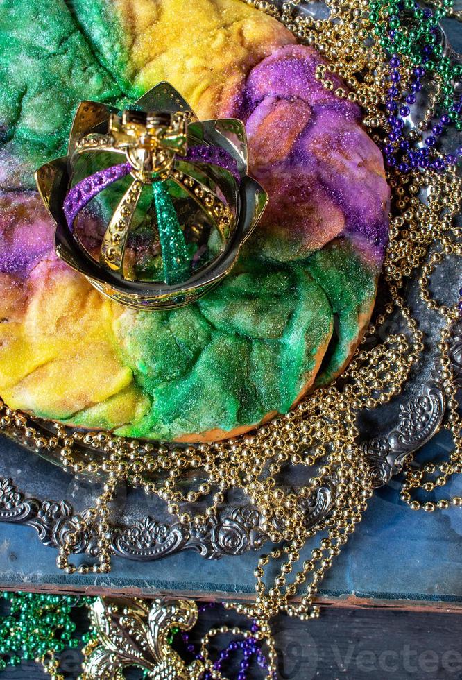 king cake with crown surrounded by mardi gras beads top view photo