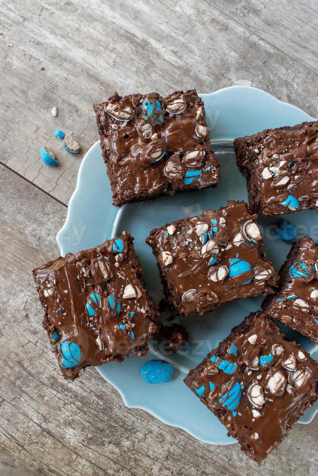 brownie squares with bright blue candy pieces and drizzled chocolate on top flat lay photo