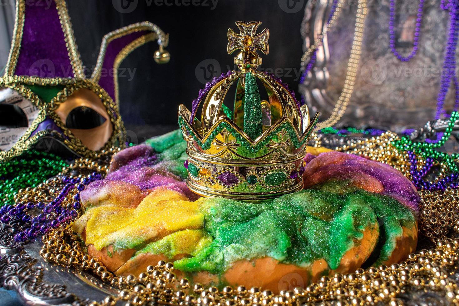 pastel de rey colorido con corona rodeada de cuentas de mardi gras foto