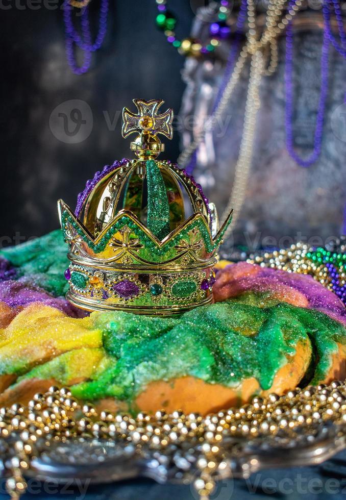 Colorful king cake with crown surrounded by mardi gras beads photo