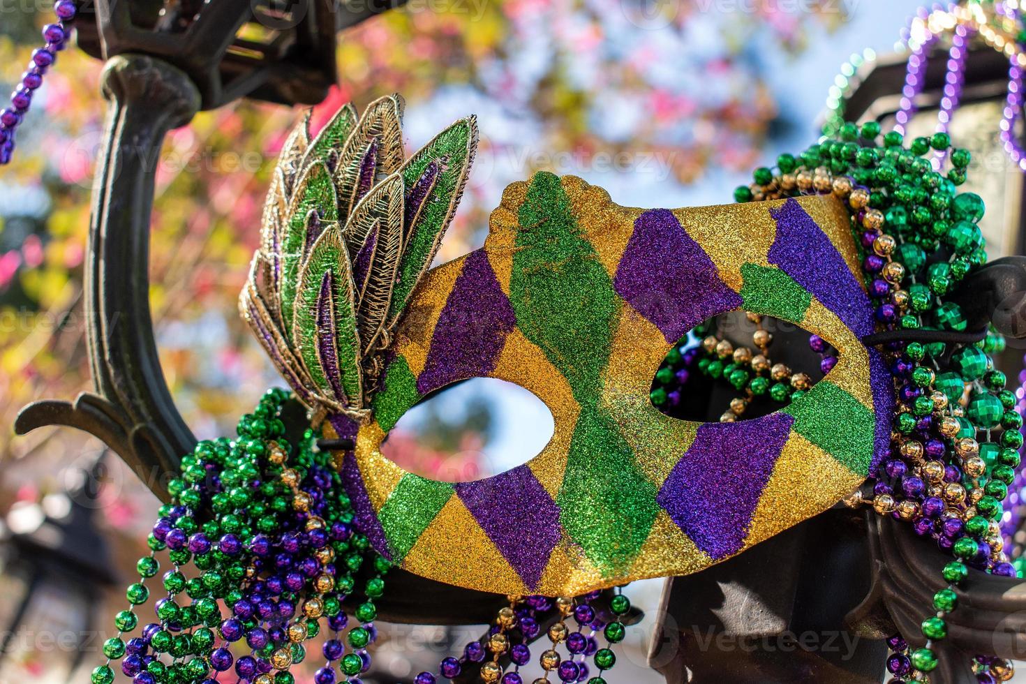 Outdoor Mardi Gras beads and mask on light post in sunshine photo