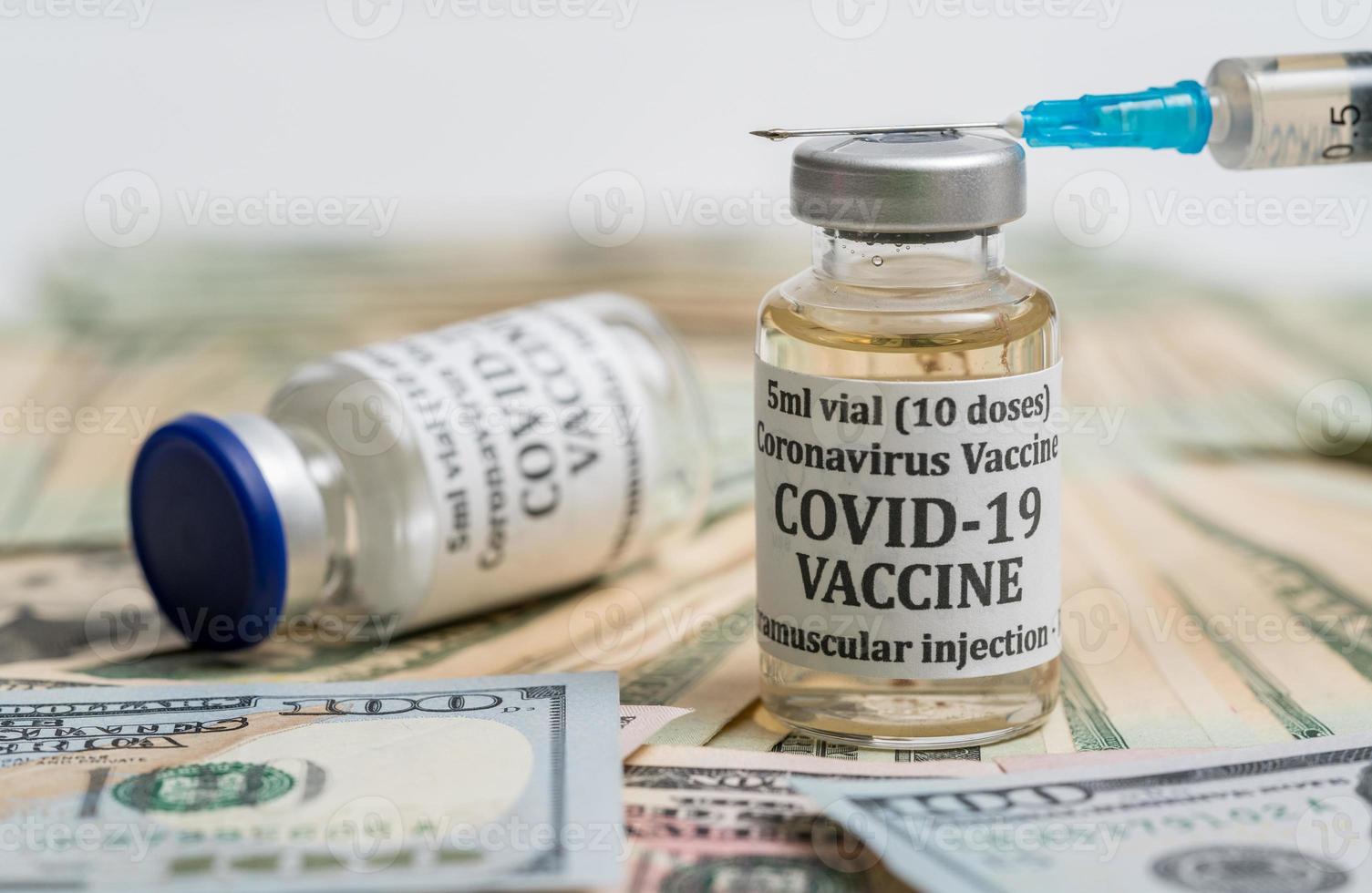 Close up of hypodermic syringe on bottle of Covid-19 vaccine with cash photo