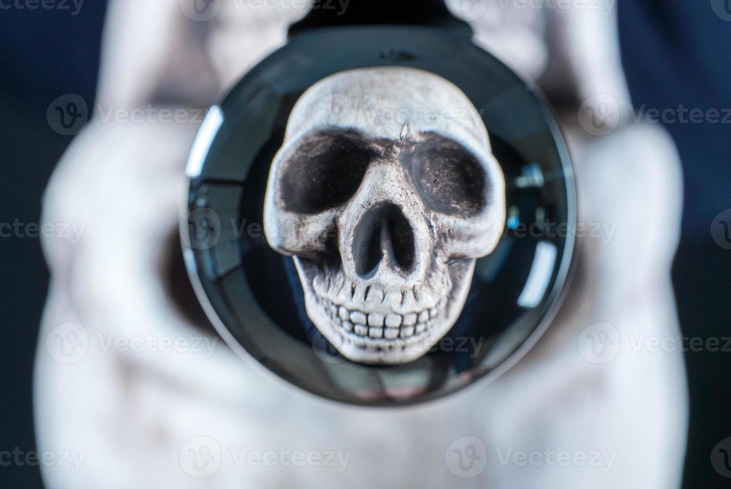 Human skull reflected in a glass ball with the original skull behind for Halloween photo