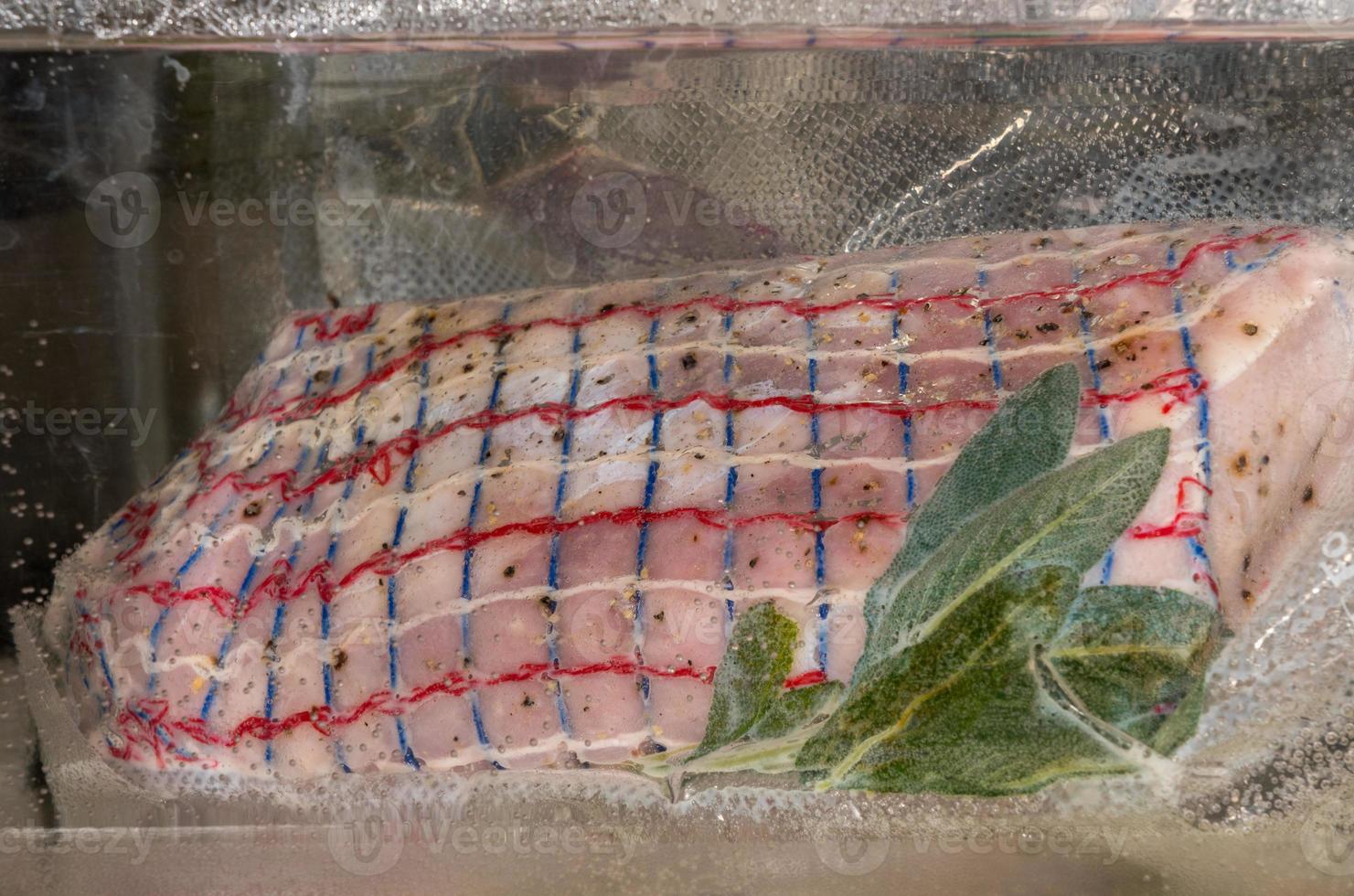 Piece of pork loin or tenderloin sealed in vacuum bag and immersed in water bath for sous vide photo