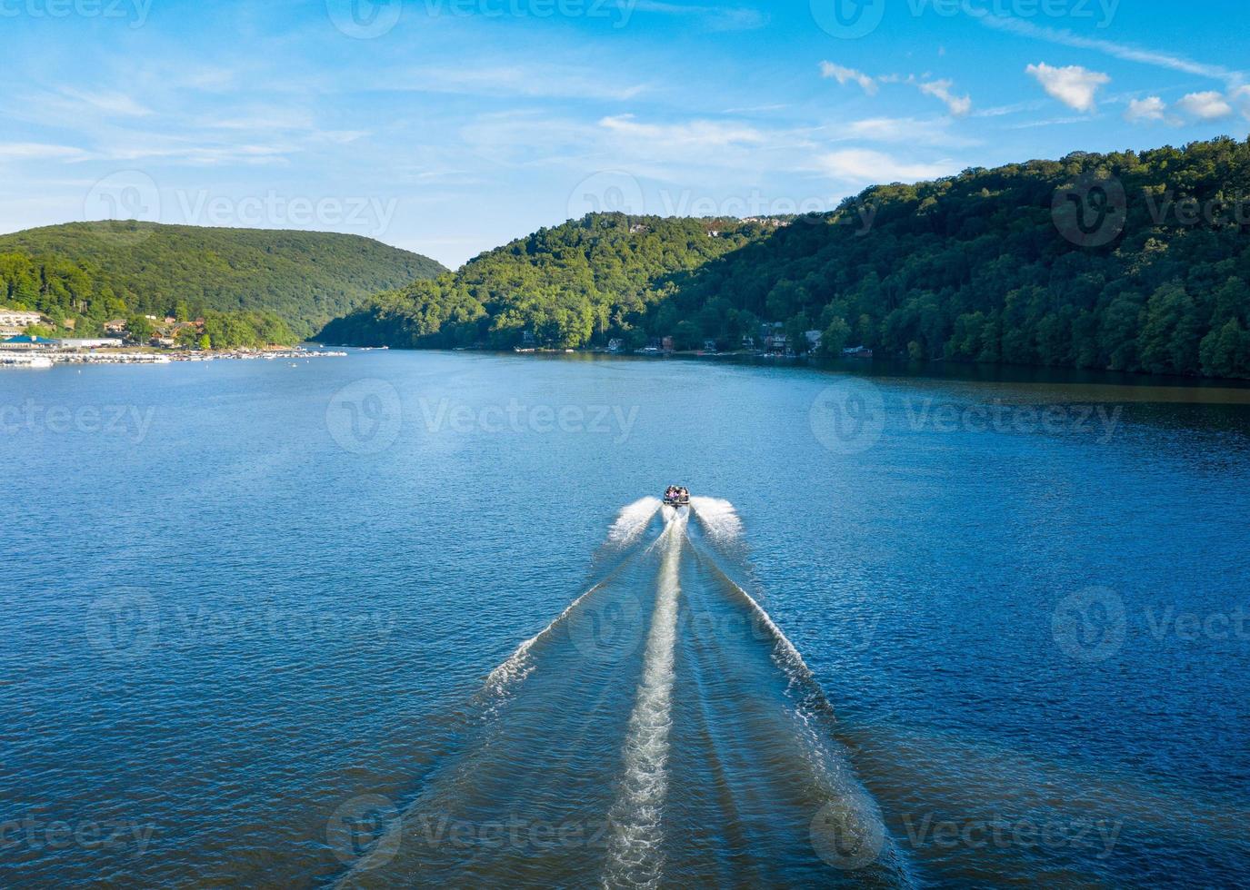 Speedboat on Cheat Lake on a summer evening with boats docked in marina photo
