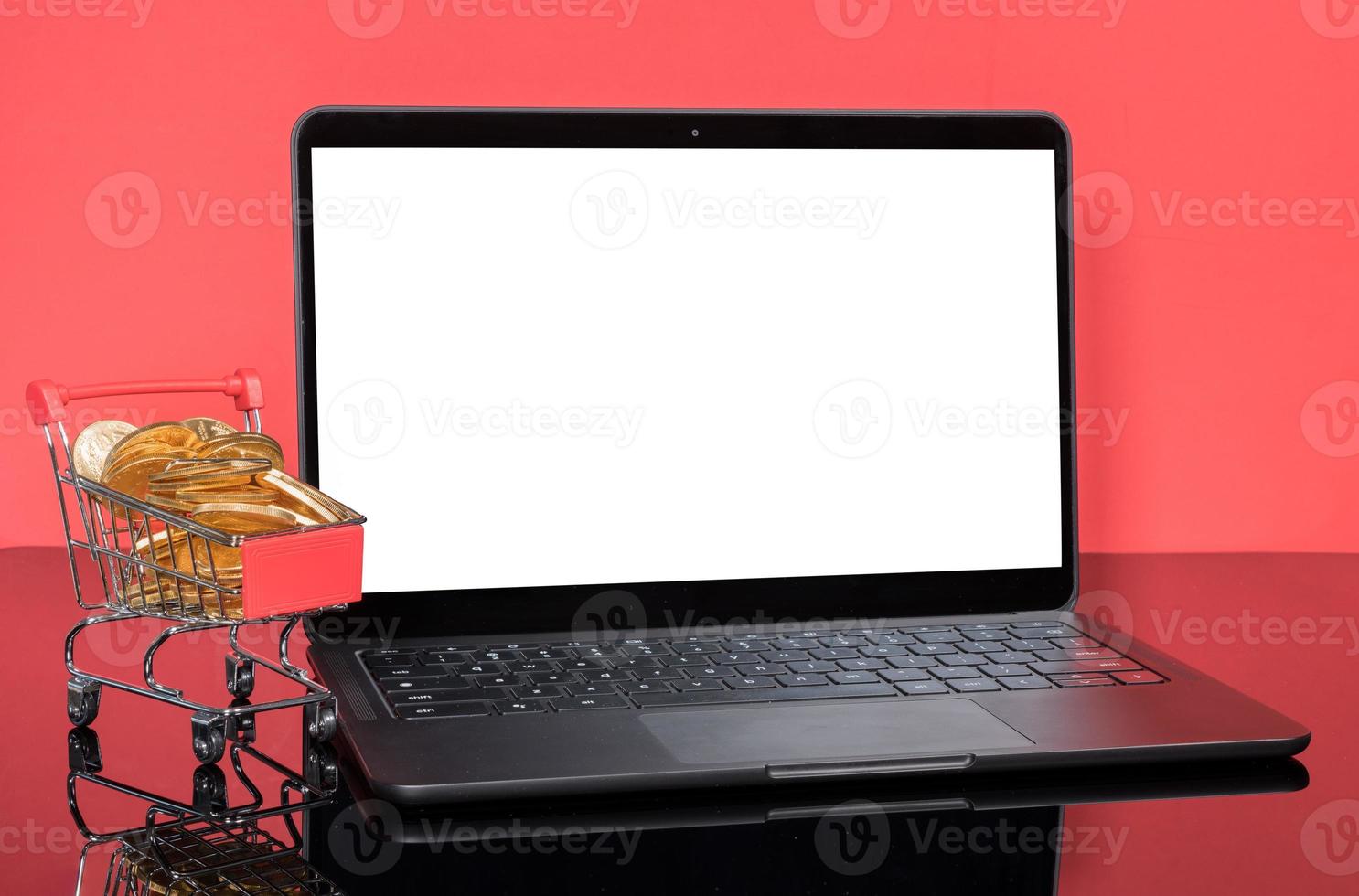 Modern laptop computer with shopping cart filled with gold coins photo