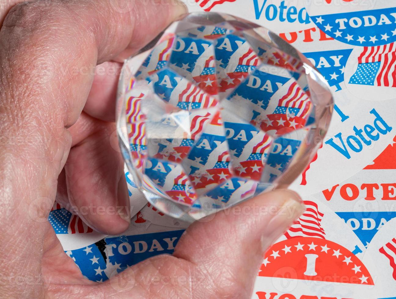 Hand holding prism over election campaign badges as concept for confused election result photo