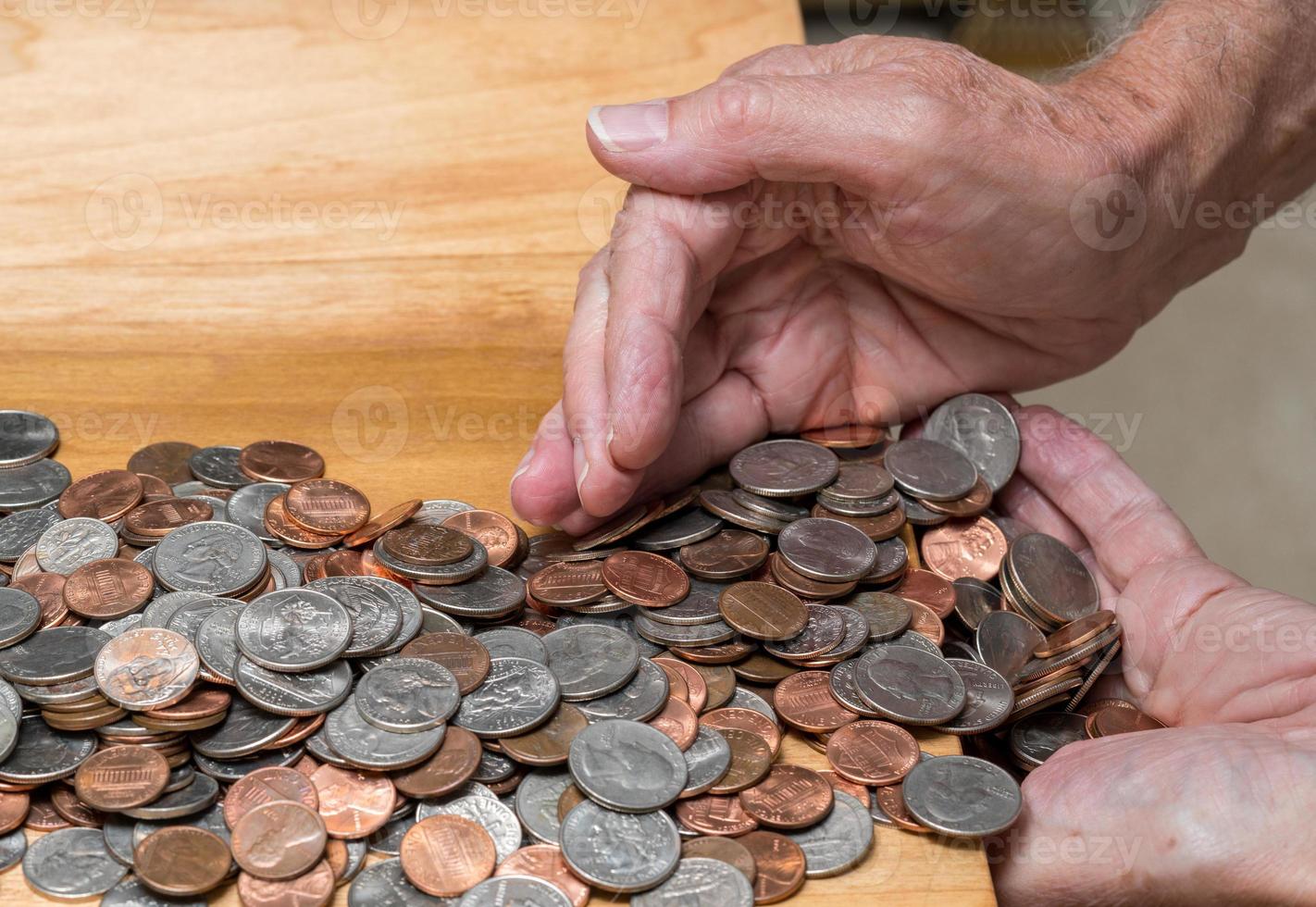 Manos recogiendo cambio suelto de EE. UU. Con monedas mixtas en una mesa de madera foto