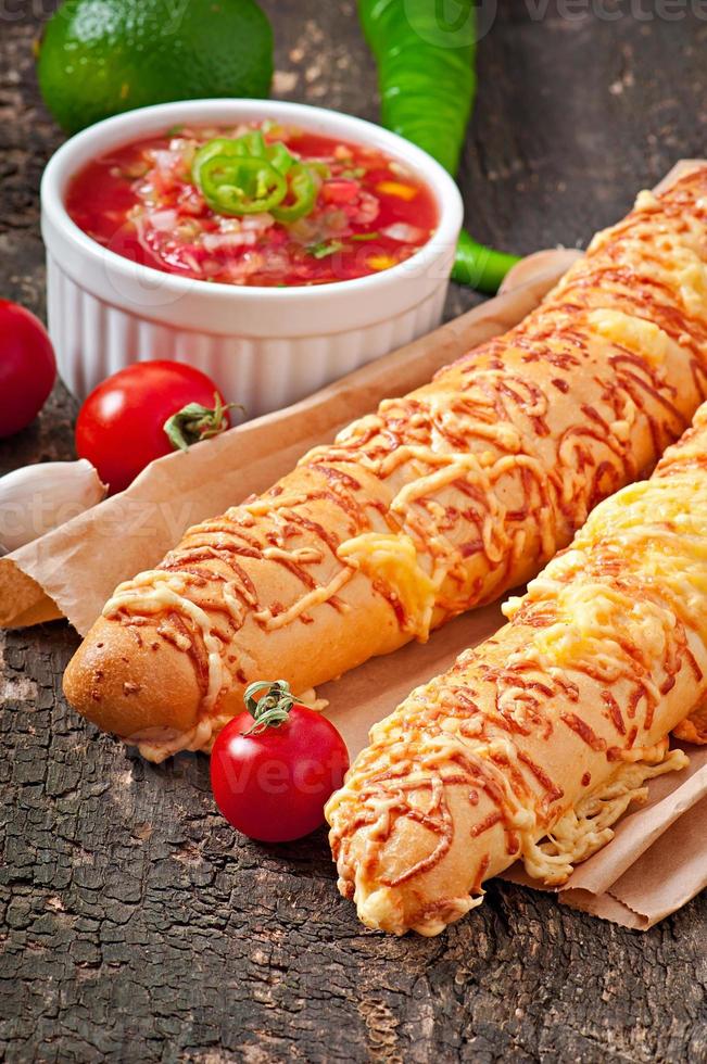 Salsa dip in bowl of bread and cheese sticks on wooden background photo