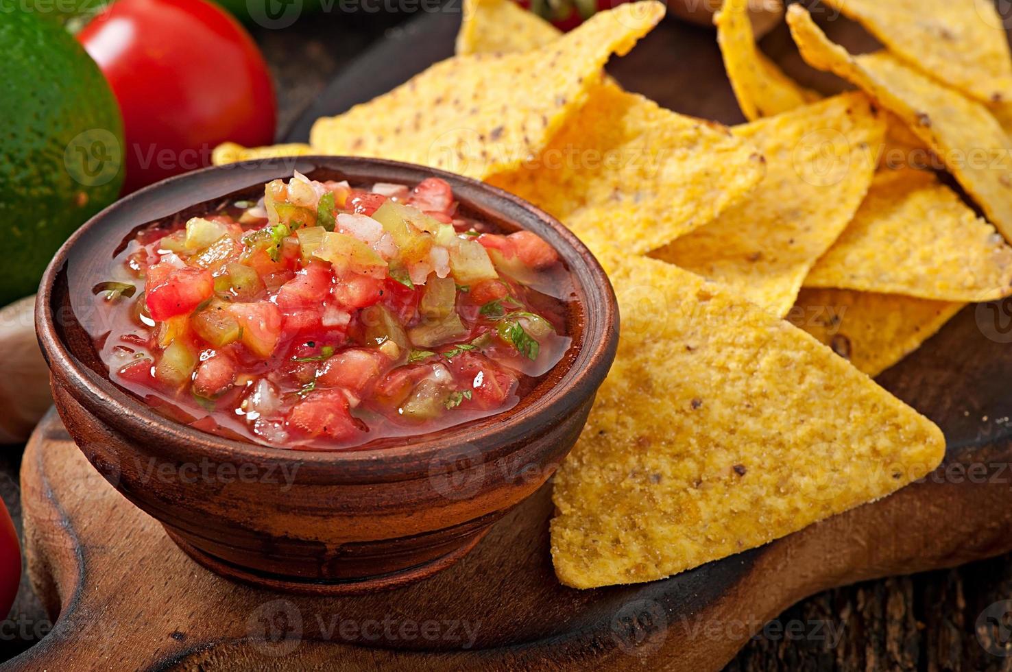 Mexican nacho chips and salsa dip in  bowl on  wooden background photo