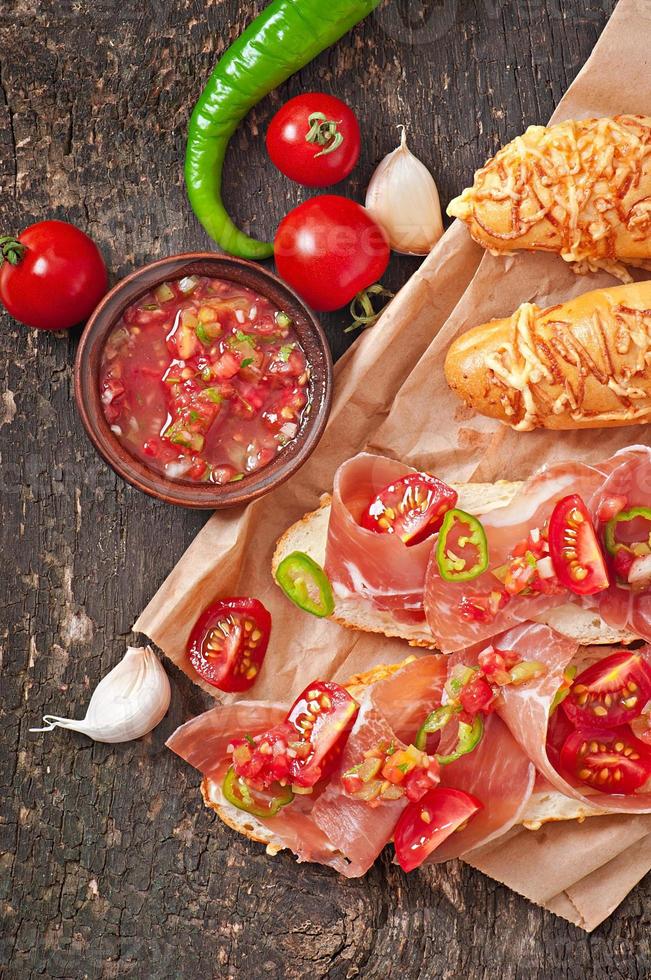 Salsa dip in bowl of bread and cheese sticks on wooden background photo