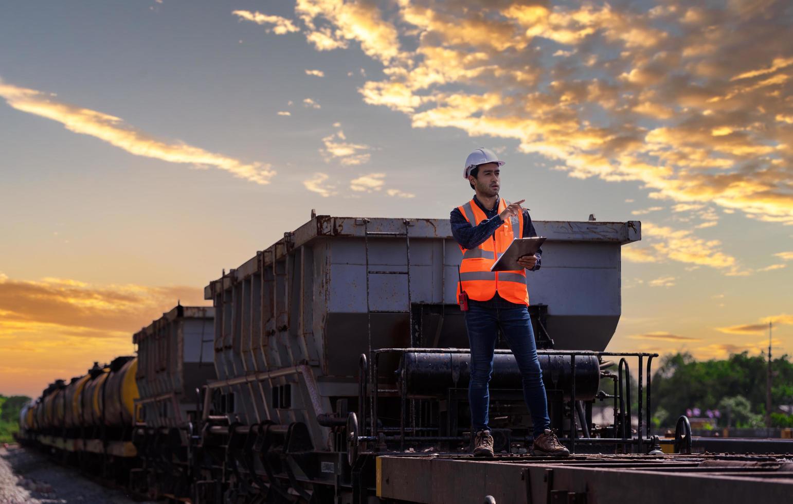 ingeniero ferroviario bajo control del proceso de construcción prueba de trenes y control del trabajo ferroviario en la estación de ferrocarril con comunicación por radio. ingeniero con uniforme de seguridad y casco de seguridad en el trabajo. foto