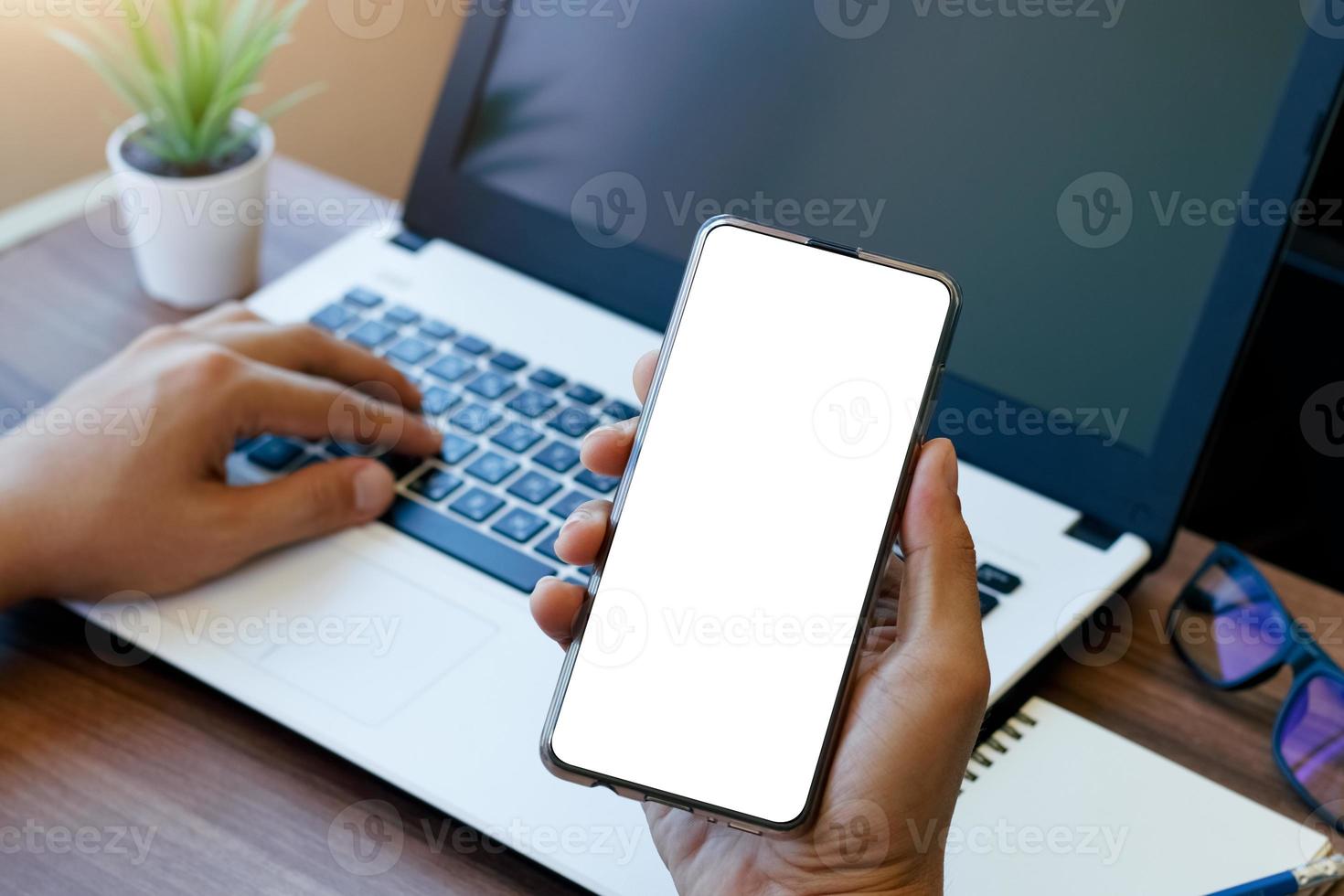 teléfono de espacio de copia de maqueta, teléfono inteligente de mano de hombre con pantalla de copia blanca en blanco para su publicidad y mensaje o contenido de información, móvil en el escritorio en la cafetería. foto