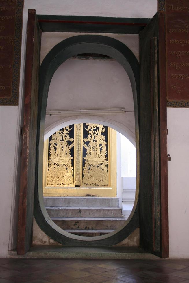 Chanel and painted black wood frame between walk way in Phra Pathom Chedi temple, Thailand. Background is a native ancient golden drawing pattern on door. photo