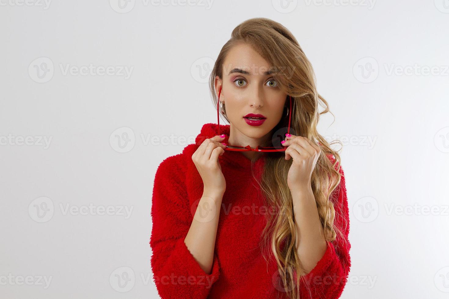 Closeup woman face with red lips, sunglasses hoodie isolated on white background. Fashionable girl in stylish outfit. Makeup, beauty concept. Winter autumn clothes. Shock excited female face. Close up photo