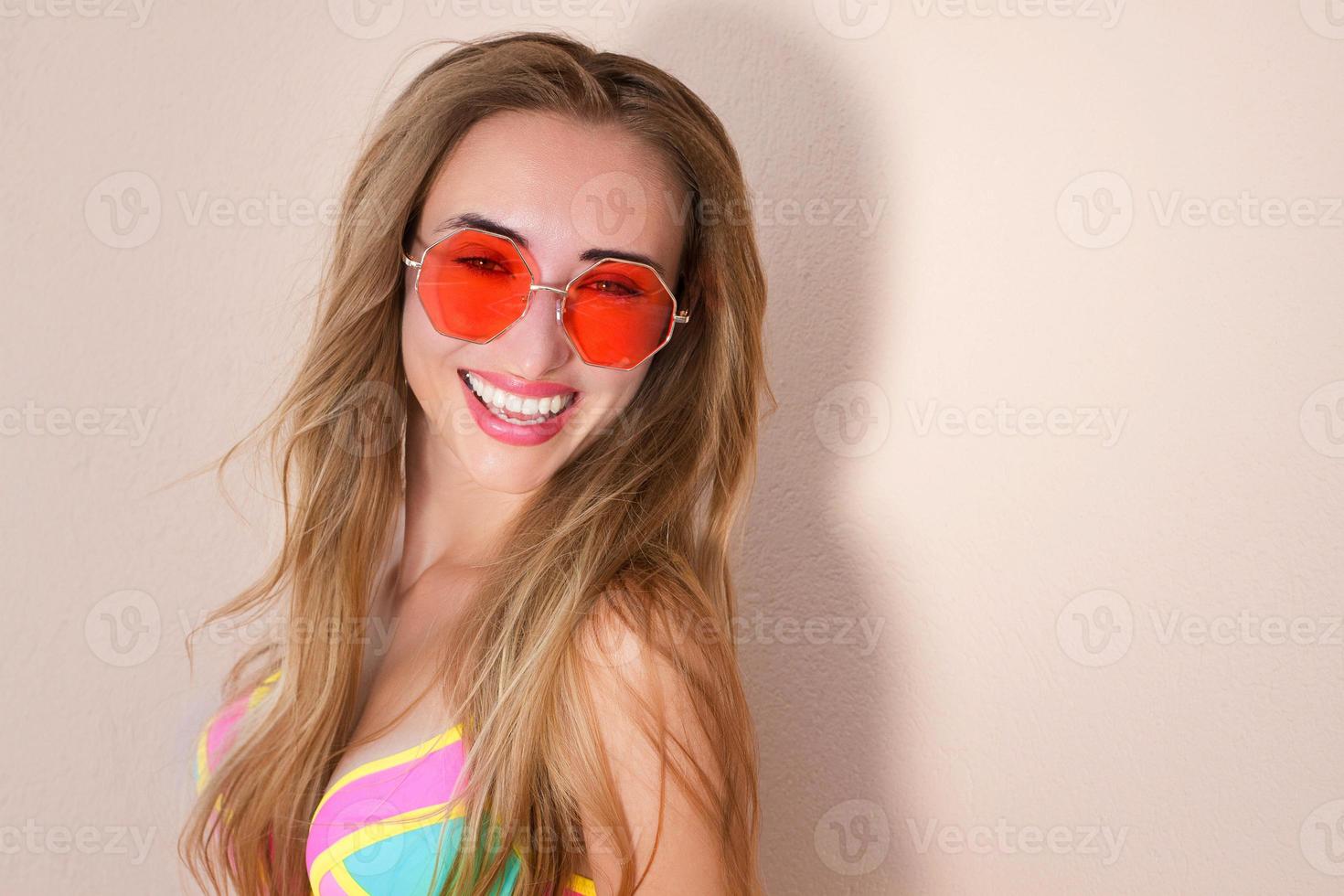 Close Up Of Happy Girl in pink sunglasses isolated. Summer holidays and fun time weekend. Summertime concept. Smiling young woman in fashion swimsuit. Selective focus. Beach Summer outfit. Copy Space photo