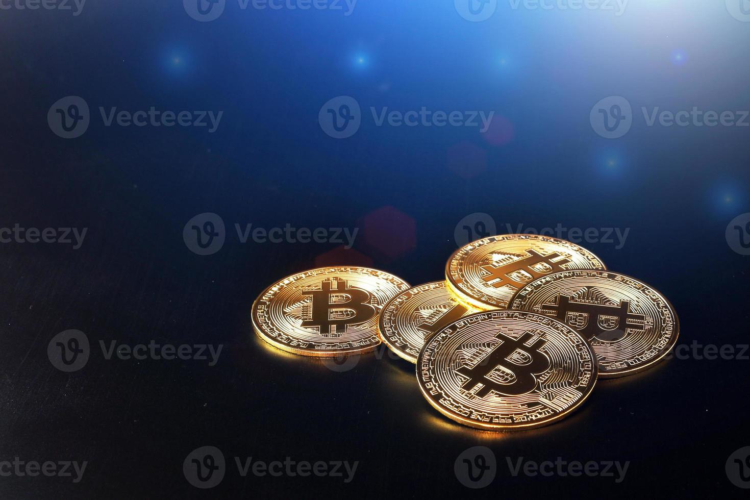 Close up golden bitcoin coin on shiny black background with blue light like space. Cryptocurrency symbol. Many shiny bitcoins gold coins lay on dark background with copy space. photo