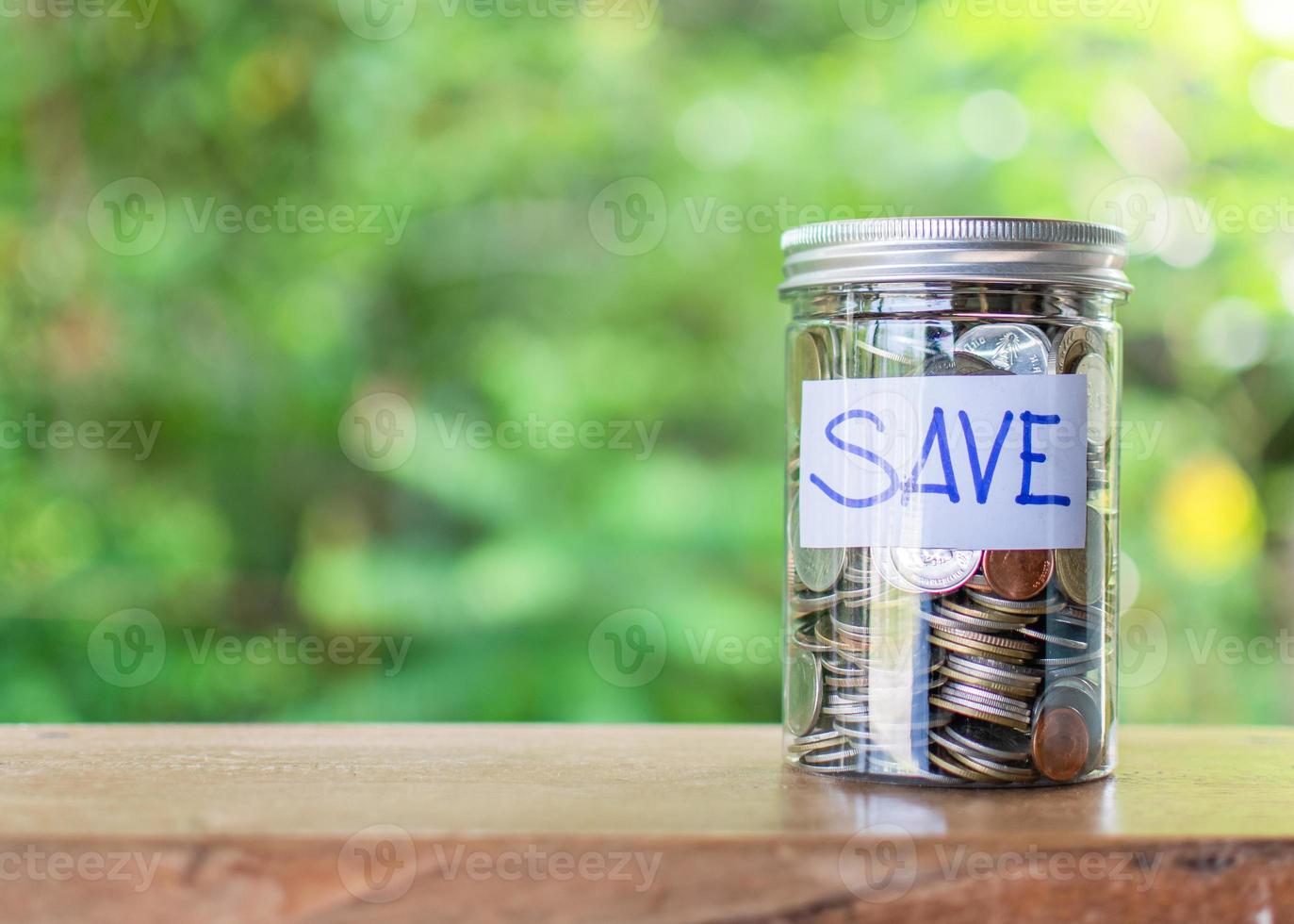Blurred background, Coins and text SAVE in a glass jar placed on a wooden table. Concept of saving money for investment and emergency situations Or during the coronavirus COVID-19 outbreak. Close up photo