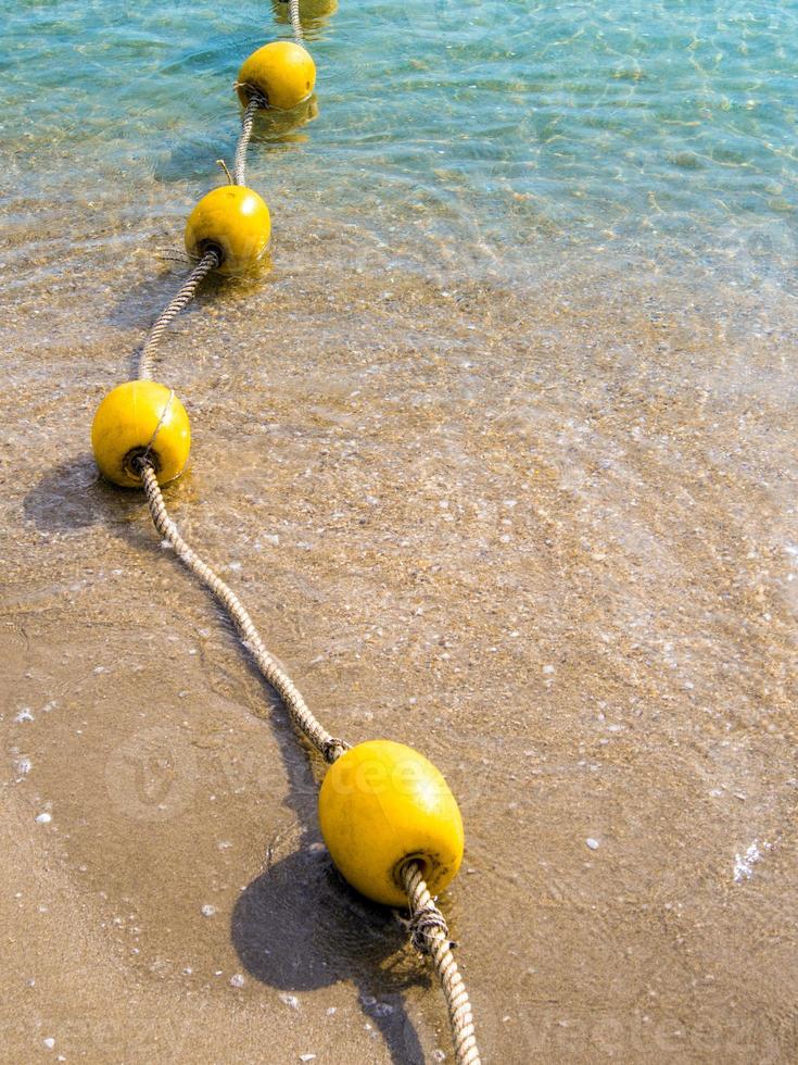 Floating buoy and rope dividing the area on the beach photo