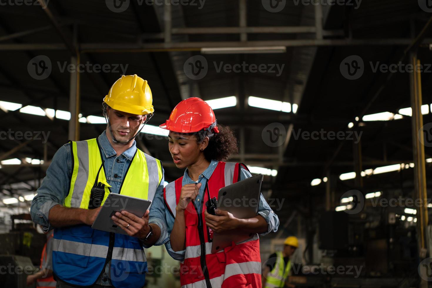 el ingeniero jefe extranjero vino a inspeccionar la vieja fábrica mecánica. hay una mecánica africana explicando detalles e informes de progreso foto